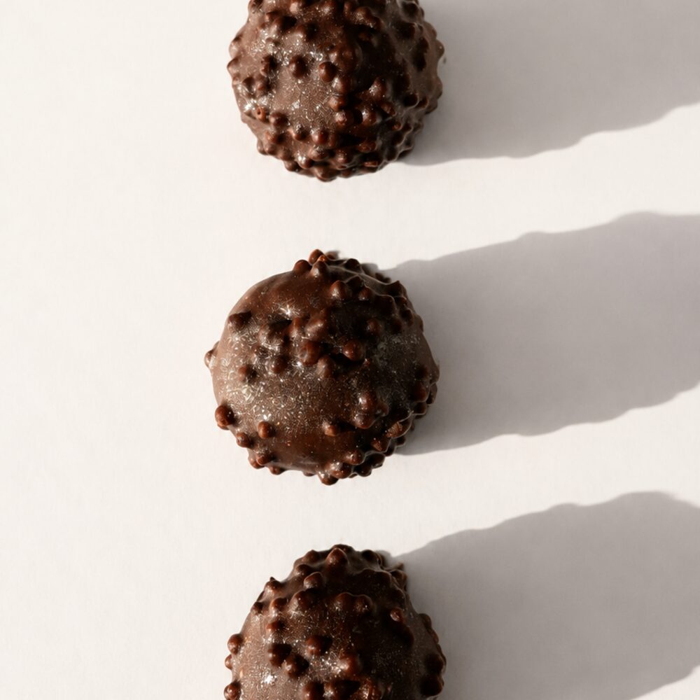 A BITEY protein chocolate coated in dark Belgian chocolate with a crisp pearl finish
