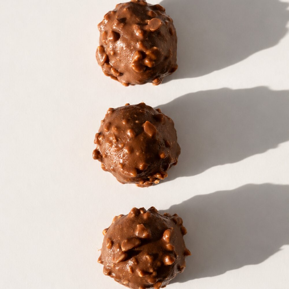 A BITEY protein chocolate coated in milk chocolate and rolled in chopped roasted hazelnut