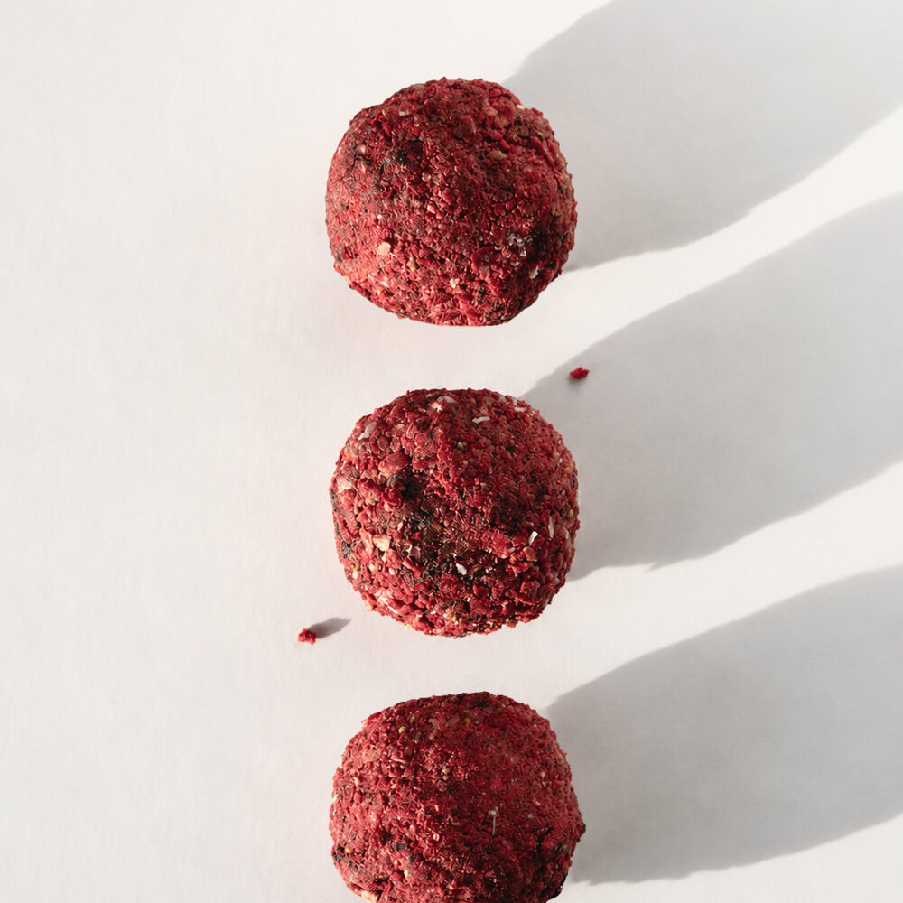 A BITEY protein chocolate rolled in freeze-dried wild berry pieces