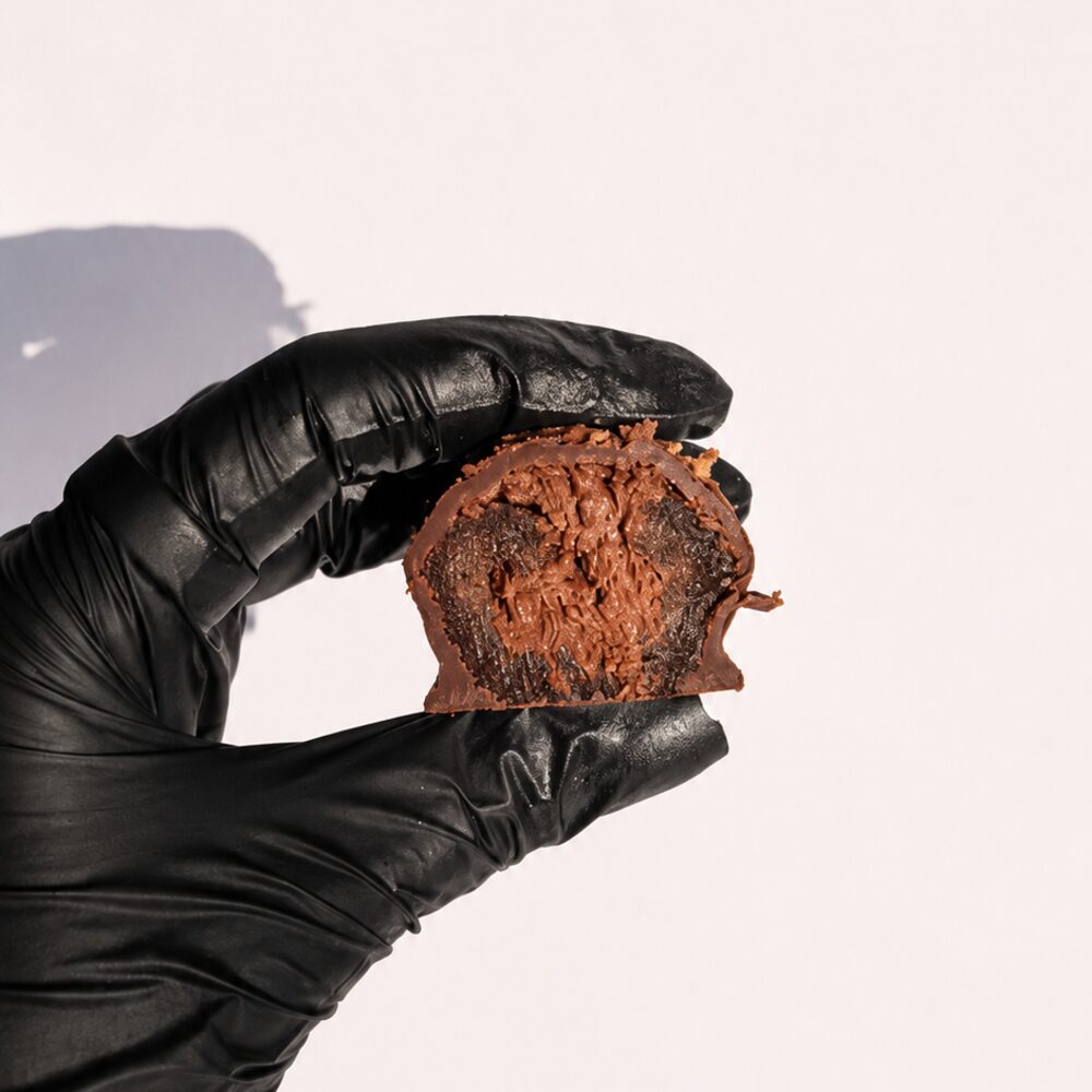 A royal date filled with chocolate cream and crispy kataifi, cut open to show the filling, on white